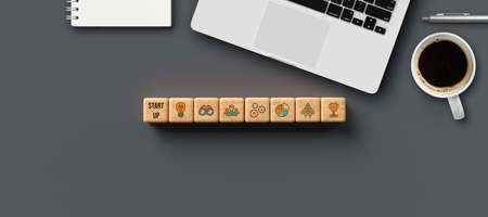 cubes with word START-UP and tech icons with office equipment on gray background