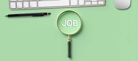 magnifying glass with the word JOB and office equipment on light green backgroundの写真素材
