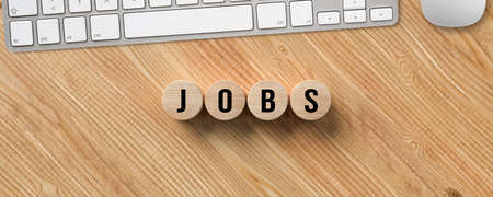 computer keyboard and cylinders with message JOBS on wooden backgroundの写真素材