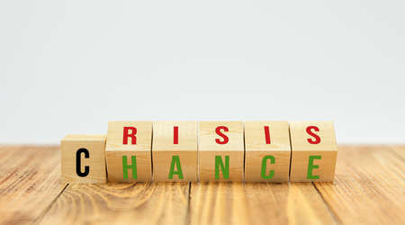 flipping cubes showing both words CRISIS and CHANCE at the same time on wooden table and white...