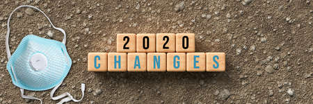 cubes with message 2020 CHANGES and a face mask on dirt gravel background