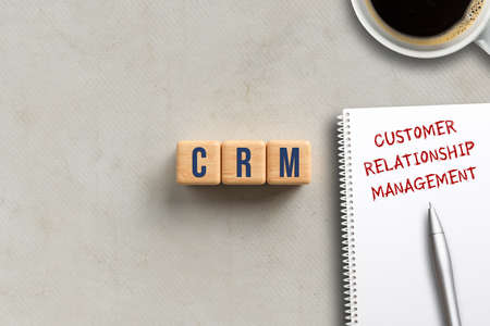 acronym CRM on cubes and notepad with explanation CUSTOMER RELATIONSHIP MANAGEMENT on paper backgroundの写真素材