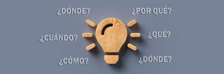 wooden lightbulb with the Spanish words for WHEN, WHAT, WHERE, WHO, WHY and HOW on colorful background - 3d illustrationの写真素材
