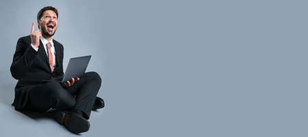 happy businessman with laptop and idea gesture on grey background
