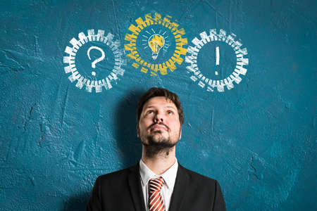 businessman having an idea in front of a plastered wall