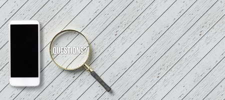 magnification glass with text QUESTIONS? and a smartphone on wooden backgroundの写真素材