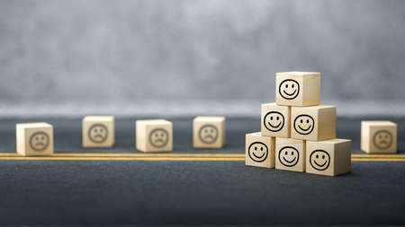 cubes with happy emoticons as a group and unhappy ones in the back on concrete background - 3d illustrationの写真素材