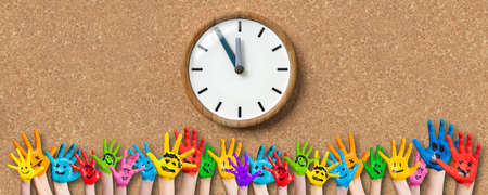 painted kids hands with smiley emoticons in front of cork background with a clockの写真素材