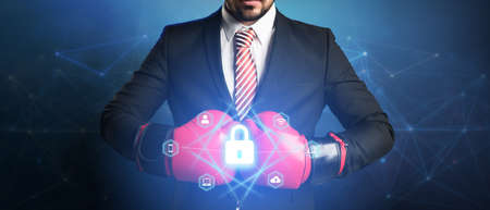 businessman with boxing glove and digital interface showing devices around a lock symbol on abstract...