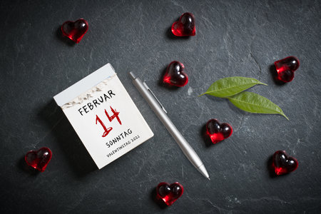 tear-off calendar with Valentine's Day 2021 in German and heart decoration on top on slate backgroundの写真素材