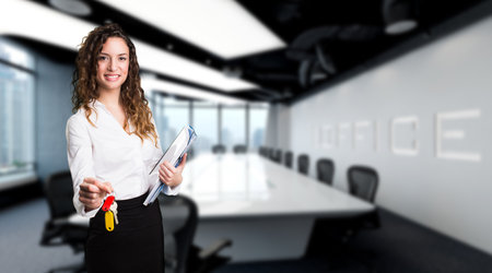 businesswoman ready to hand over keys in front of a conference room scene