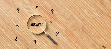 magnification glass with text ANSWERS surrounded by question marks on wooden background - 3d illustrationの写真素材