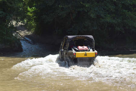 The man on the ATV crosses a stream. Tourist walks on a cross-country terrain.の写真素材
