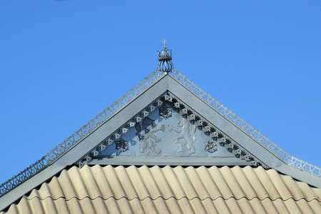 Decorative elements on the ridge of the roof. The roof of slate and horse of the decorative sheet. Lions and flowers from the sheet metal on the front.の写真素材