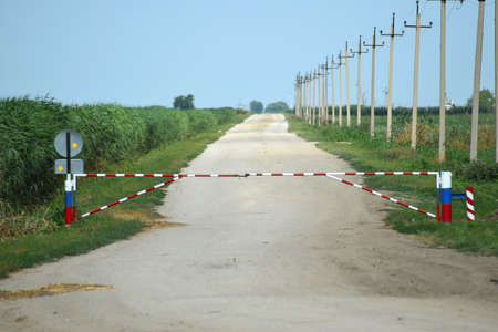 Road closed barrier. Dirt road among the agricultural fields. Closed Zone.
