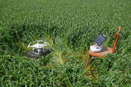 Quadrocopters on a plastic box among the wheat stalks and control panel with a clipboard on a chair....
