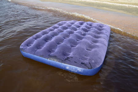 Blue inflatable mattress swimming in the pond. An inflatable mattress on the beach.の写真素材