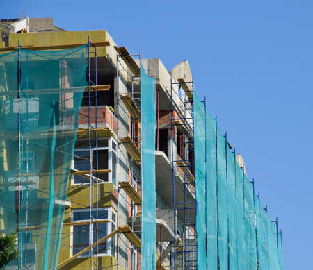 Safety net in the newly built high-rise building. Green grid on building of objects falling from a...
