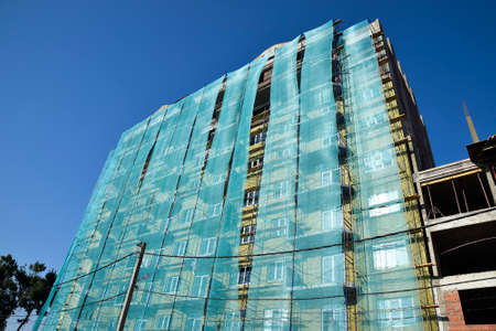 Safety net in the newly built high-rise building. Green grid on building of objects falling from a height.の写真素材