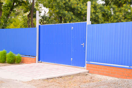 Blue gate and fence. Fence of the private house with blue fence and a gate.の写真素材