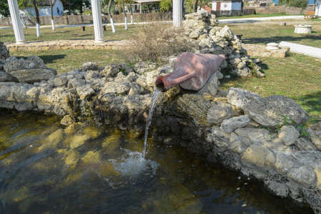 Water pouring from a jug into a pond. Decorative pond.の写真素材