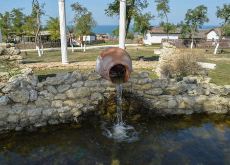 Water pouring from a jug into a pond. Decorative pond.の写真素材