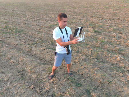 The man is holding a remote control from the quadrocopters. Photographer's work with gadgets.