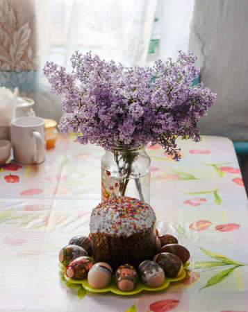 Bouquet of lilacs near Easter cakes and colored eggs
