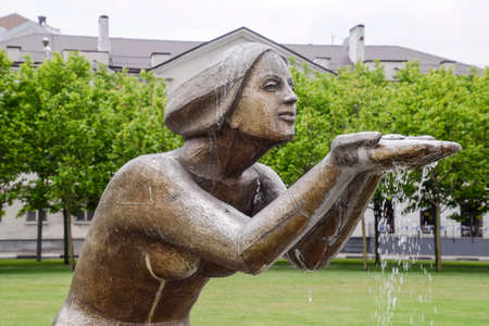 Statue of kneeling woman in the fountain. Water flowing from the hands of the statue.の写真素材