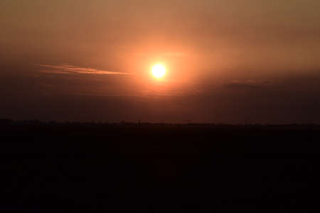Tractor plowing plow the field on a background sunset. tractor silhouette on sunset background.の写真素材