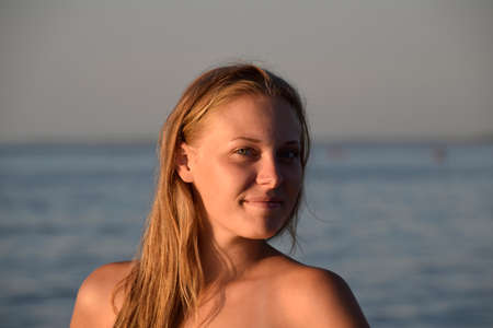 Blond girl in a bikini standing in the sea water. Beautiful young woman in a colorful bikini on sea...