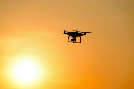 Quadrocopters silhouette against the background of the sunset. Flying drones in the evening sky.の写真素材
