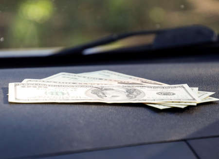 Dollars on a car dashboard under the windshield. American Money.の写真素材