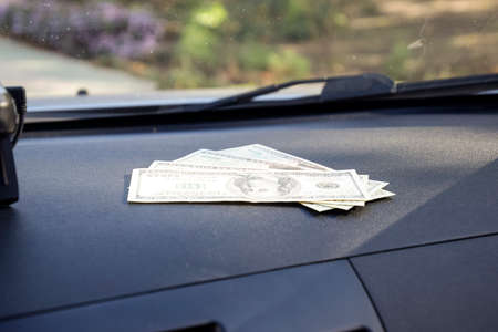 Dollars on a car dashboard under the windshield. American Money.