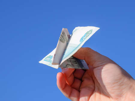 Denominations of Russian money, folded in the airplane against the blue sky in hand.の写真素材