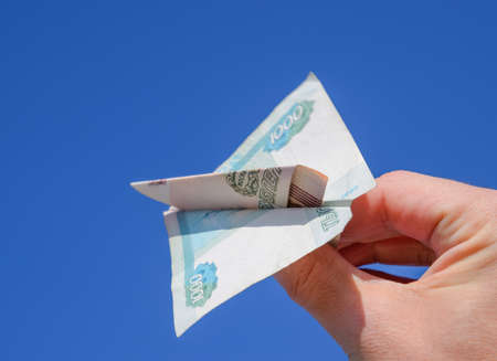 Denominations of Russian money, folded in the airplane against the blue sky in hand.の写真素材
