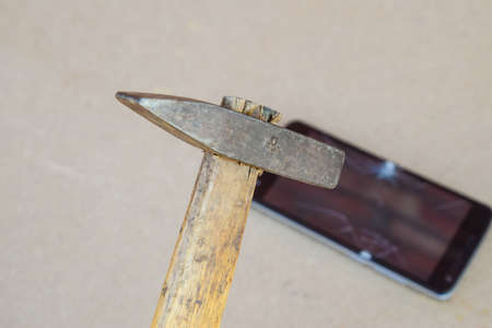 Hammer and smartphone. The screen of the smartphone, a broken hammer. The destruction of the phone.の写真素材
