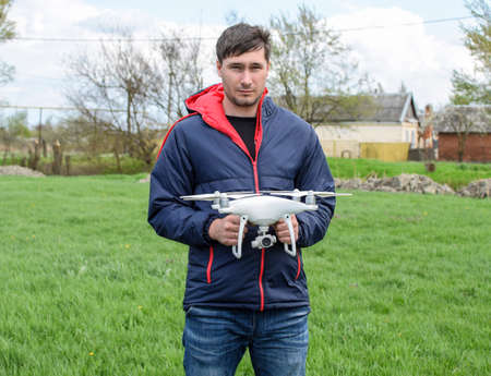 A man with a quadrocopter in his hands. A white drone is being prepared for the flight. Phantom