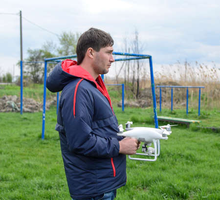 A man with a quadrocopter in his hands. A white drone is being prepared for the flight. Phantom