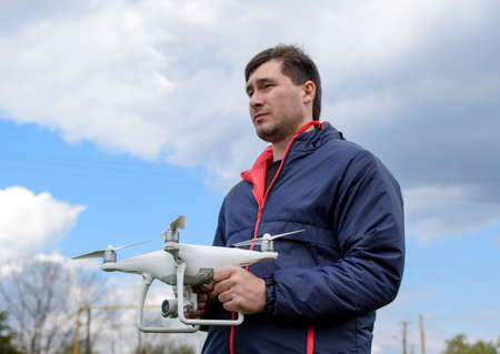 A man with a quadrocopter in his hands. A white drone is being prepared for the flight. Phantomの写真素材