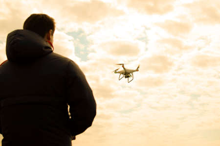 A man with a remote control in his hands. Controlling the flight of the drone against the sky. Phantomの写真素材