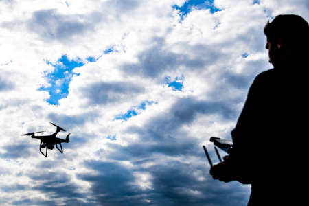 A man with a remote control in his hands. Controlling the flight of the drone against the sky. Phantomの写真素材