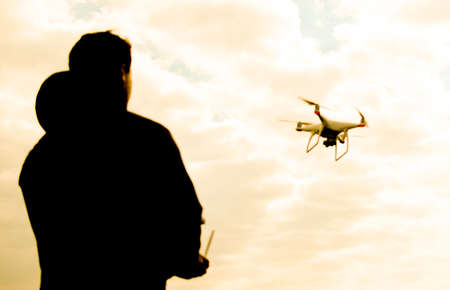 A man with a remote control in his hands. Controlling the flight of the drone against the sky. Phantomの写真素材