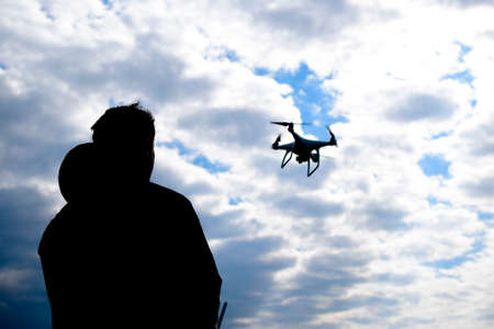 A man with a remote control in his hands. Controlling the flight of the drone against the sky. Phantomの写真素材