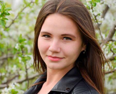 Beautiful fairy young girl in a flowering plum garden. Portrait of a girl on a white flowers background.の写真素材