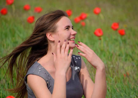 Beautiful fairy young girl in a field among the flowers of tulips. Portrait of a girl on a background of red flowers and a green field. Field of tulips.の写真素材