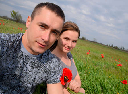 A girl and a guy are sitting together outdoors. A young couple. Relationships of young people. Tulip in the hands.の写真素材