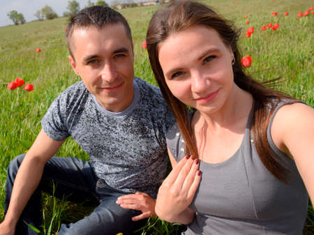 A girl and a guy are sitting together outdoors. Young couple in a field of tulips. Relationships of young people.の写真素材