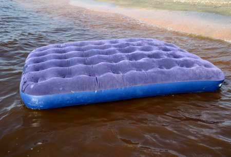 Blue inflatable mattress swimming in the pond. An inflatable mattress on the beach.の写真素材