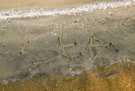 The inscription of the sea on the sand. Coastal sand and waves. Inscriptions on the shore.の写真素材